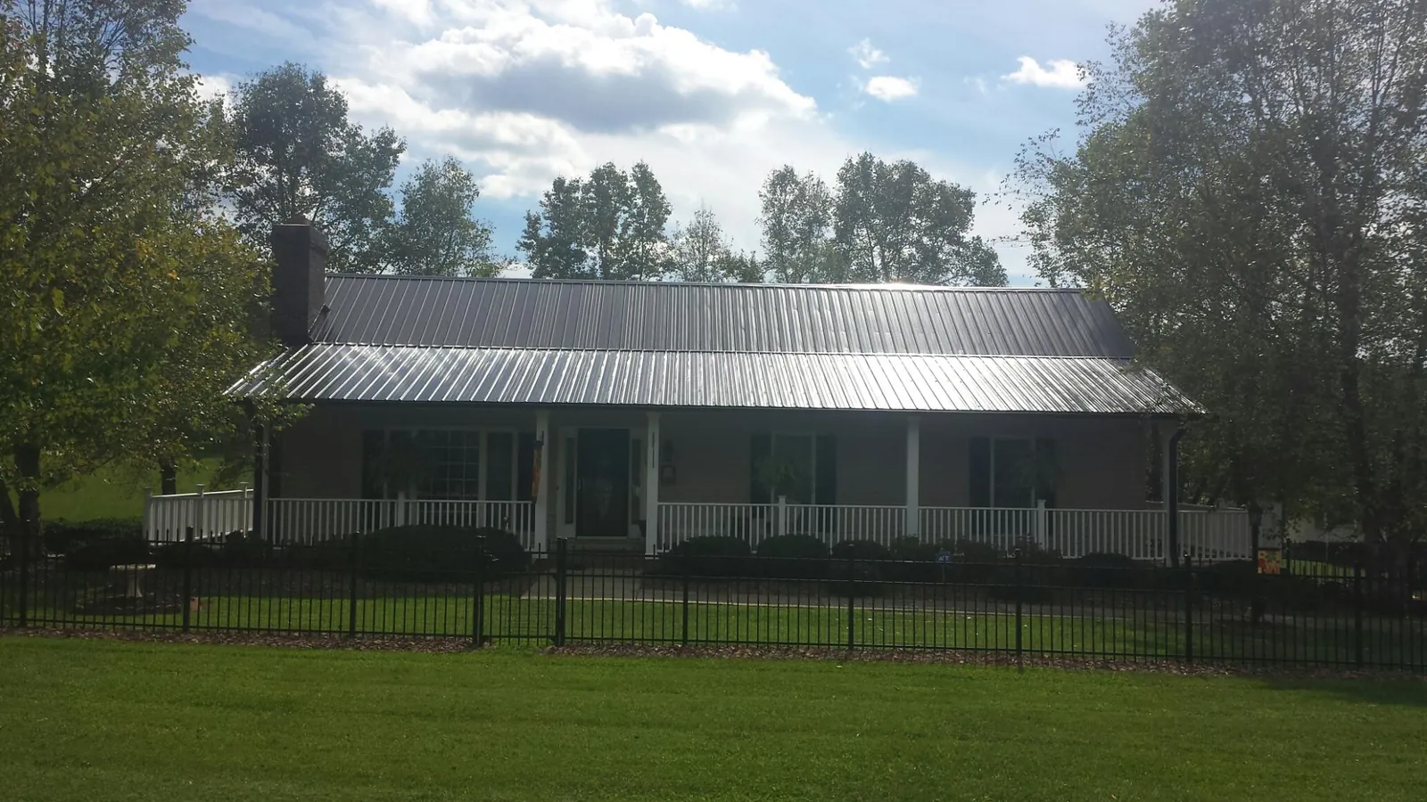 Gray metal roof on a brick ranch with a full width front porch — Gutter Guard Installation work by our crew in Bend