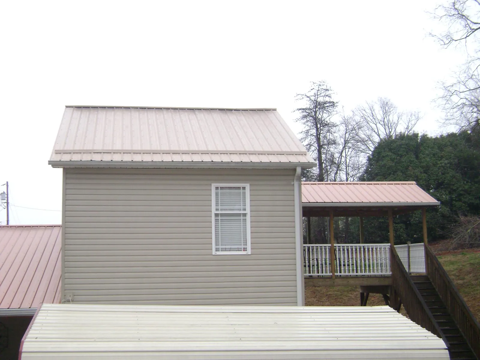 Tan metal roofs on a two story addition and attached porch, from a Roof Replacement job in Bend